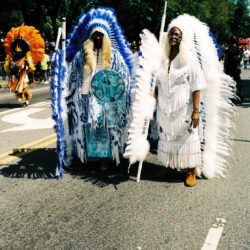 Parade participants in ornate feathered ceremonial headdresses
