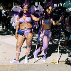 Two women in purple feathered carnival costumes