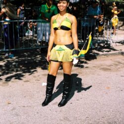Woman in yellow-green carnival outfit holding flag