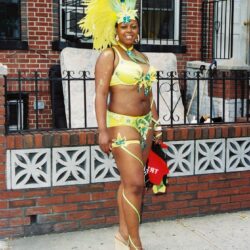 Person in yellow feathered carnival costume on sidewalk