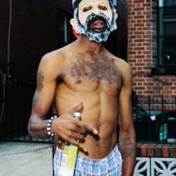 Shirtless person wearing mask, holding bottle