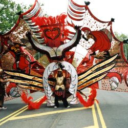 Parade performer wearing massive red and gold wings