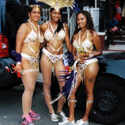Three women in gold carnival costumes on street