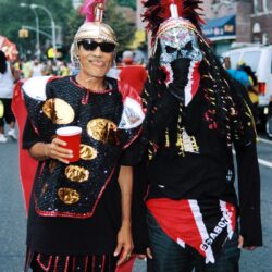 Two masked carnival revelers in colorful costumes