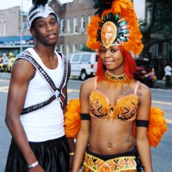 Two people in vibrant orange carnival costumes