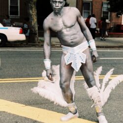 Carnival performer in white body paint and feathers