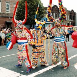 Three performers in colorful horned carnival parade costumes