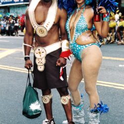 Two carnival performers wearing colorful feathered costumes