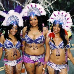 Three women in purple carnival costumes at parade