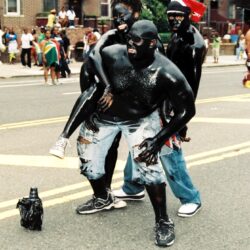 Parade participants covered in black body paint
