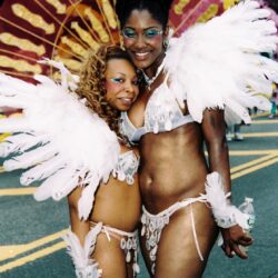 Two smiling women in feathered carnival costumes