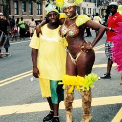 Couple in vibrant yellow carnival costumes on street
