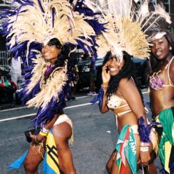 Three women in colorful feathered carnival costumes