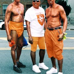 Three men in orange outfits on city street