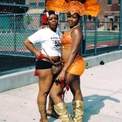Two women wearing orange carnival costumes