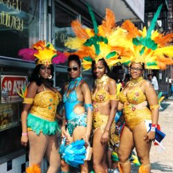 Four women in colorful feathered carnival costumes