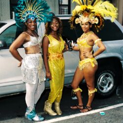 Three women in vibrant carnival costumes posing
