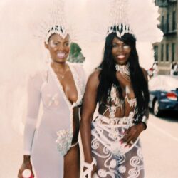 Two women smiling in feathered carnival costumes
