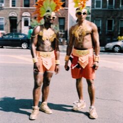 Two men in orange feathered carnival costumes