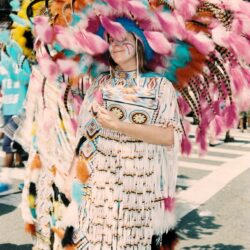 Person in colorful feathered parade regalia