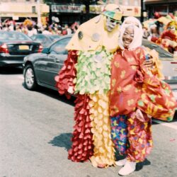 Two people in colorful carnival costumes smiling