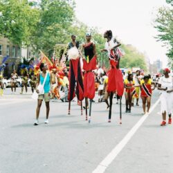 Parade performers on stilts in red costumes