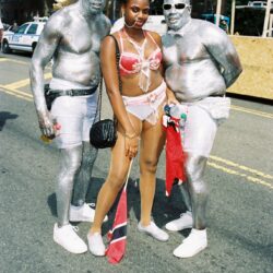 Three costumed parade participants posing on street