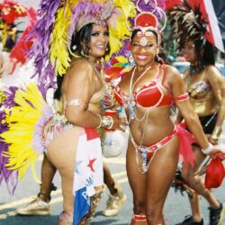 Two women in colorful carnival costumes smiling