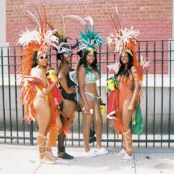 Four women in colorful carnival feathered costumes