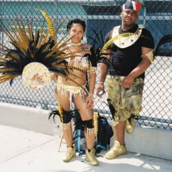 Couple in gold carnival costumes by fence