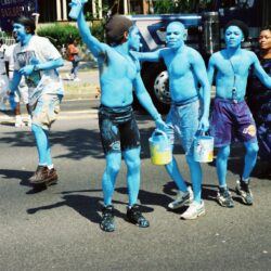 Group of blue-painted men carrying buckets