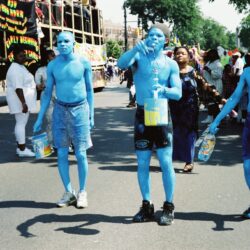 Four men painted blue walking in parade