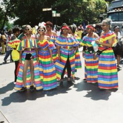 Women in rainbow-striped dresses at street parade