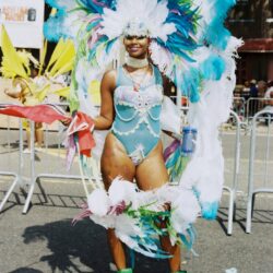 Person in turquoise feathered carnival costume