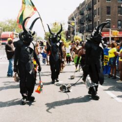 Parade participants in black horned costumes