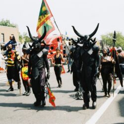 Parade participants in black horned costumes
