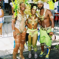 Three people in green feathered carnival costumes
