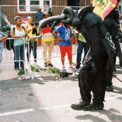 Person in black elephant costume parading with flag
