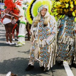 Person in yellow feathered headdress at parade