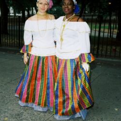 Two women in colorful traditional Caribbean dresses