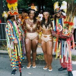 Four people in colorful feathered carnival costumes