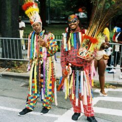Two men in colorful carnival feathered headdresses