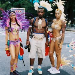 Three people in colorful carnival feathered costumes