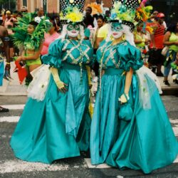 Two masked women in teal carnival costumes
