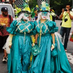 Two masked performers in teal carnival costumes