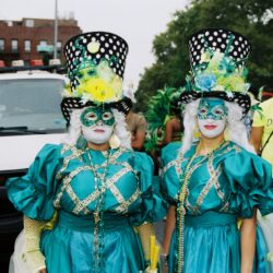 Two masked performers in teal with top hats