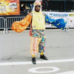 Person in colorful patchwork costume with arms outstretched