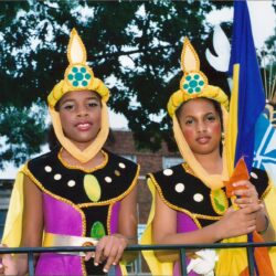 Two girls in colorful festival costumes holding flag