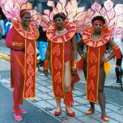 Three performers in red carnival feathered costumes