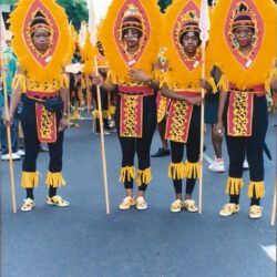 Four parade performers in yellow feathered costumes